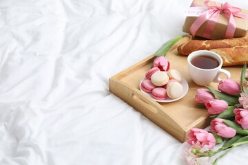 Delicious breakfast, flowers, gift box and card with phrase I Love You on bed, space for text