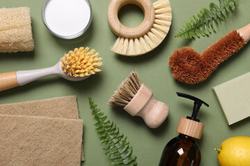 Different cleaning supplies and fern leaves on green background, flat lay