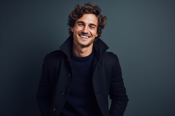 Fototapeta premium A man in a black coat and blue sweater is smiling