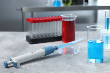 Laboratory analysis. Micropipette, petri dish, beakers and test tubes on light grey table