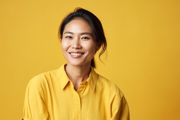 Fototapeta premium A woman in a yellow shirt is smiling and looking at the camera