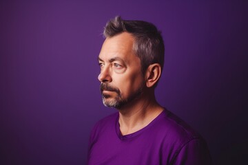 Fototapeta premium A man with a beard and gray hair is wearing a purple shirt