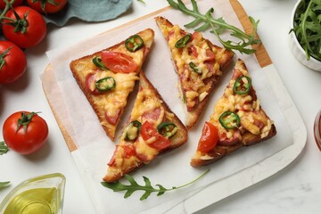 Tasty pizza toasts and ingredients on white marble table, flat lay