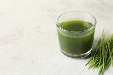 Wheat grass drink in glass and fresh sprouts on light table. Space for text