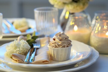 Stylish table setting with burning candles, beautiful flowers and tasty cupcake