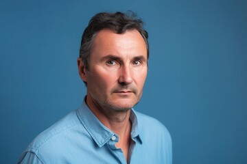 Obraz premium A man with a beard and gray hair is wearing a blue shirt