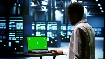Supervisor using green screen laptop to inspect supercomputers doing intense computations....