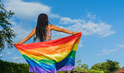 joven mujer de espaldas con la bandera del orgullo gay aal aire libre 