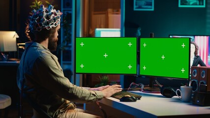 Computer engineer using EEG headset, starting mind upload process using green screen PC. Man using...