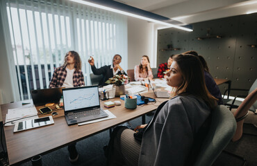 A diverse group of young professionals discusses statistics and planning during a collaborative business meeting in a contemporary office setting.