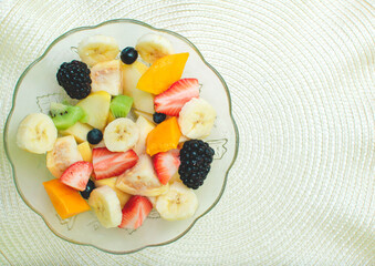 Imagen horizontal de un plato de ensalada de frutas frescas como zarzamora, mora azul, mango,...