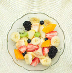 Imagen cuadrada de un plato de frutas frescas en rebanadas como wiki, manzana, plátano, mango, fresa, zarzamora, mora azul 