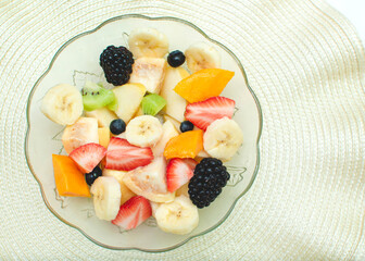 Imagen horizontal con un plato de ensalada de frutas saludables sobre un fondo claro