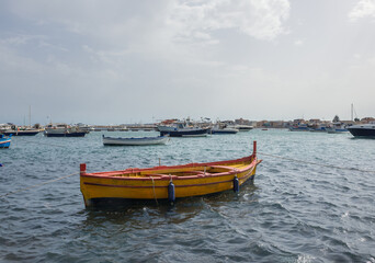 Fototapeta na wymiar Yellow fishing boat in port of Marzamemi village on the island of Sicily, Italy