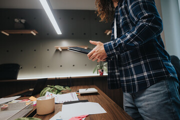 A young male office worker in a plaid shirt gestures actively during a business discussion in a...