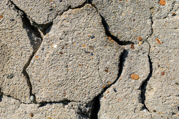A cracked concrete wall with a lot of small rocks