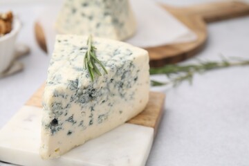 Tasty blue cheese with rosemary on light table, closeup. Space for text
