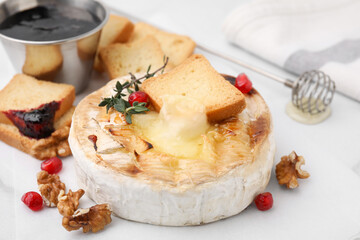 Tasty baked camembert with crouton, thyme, walnuts and pomegranate seeds on white table, closeup