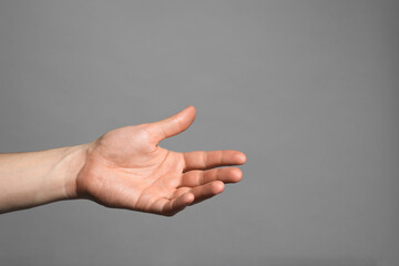 Man holding something in hand on grey background, closeup. Space for text