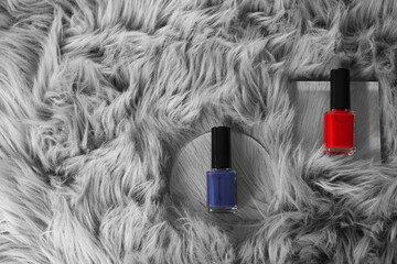 Bright nail polishes in bottles on grey faux fur, top view. Space for text