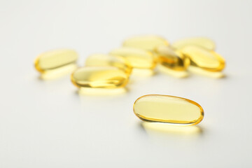 Yellow vitamin capsules on white background, closeup