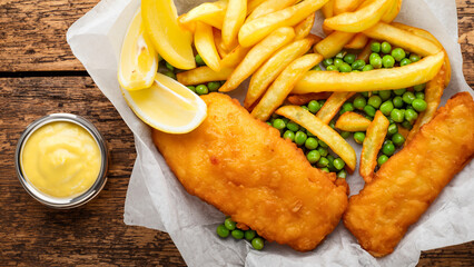 delicious crispy fish and chips - fried cod, chips, lemon wedges, tartar sauce and mushy peas on paper