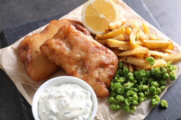 Tasty fish, chips, sauce and peas on grey table, closeup