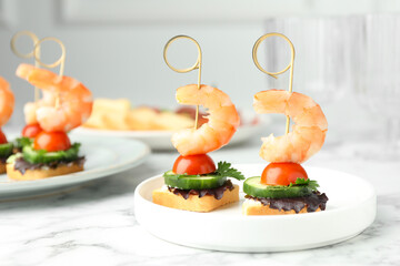 Tasty canapes with shrimps, cucumber, greens and tomatoes on white marble table, closeup