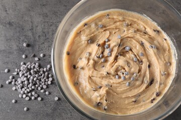 Raw dough with chocolate chips in bowl on grey table, flat lay