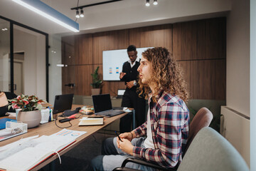 A multiracial group of young professionals collaborating in a modern office meeting room, focusing on growth and financial charts. The setting is professional and underscores teamwork and detailed