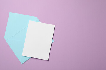 Letter envelope and card on violet background, top view. Space for text