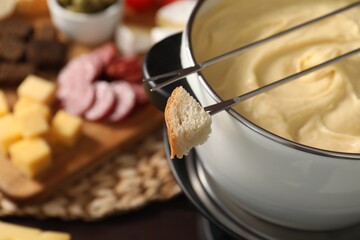 Fondue with tasty melted cheese, forks and piece of bread on table, closeup. Space for text