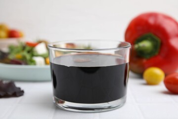 Vinegar in glass on white tiled table, closeup