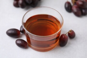 Wine vinegar in glass bowl and grapes on light grey table, closeup
