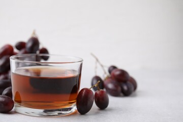 Wine vinegar in glass bowl and grapes on light grey table, space for text