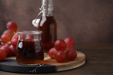 Wine vinegar in glass jar and grapes on wooden table