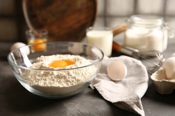 Making dough. Flour with egg yolk in bowl on grey table, closeup