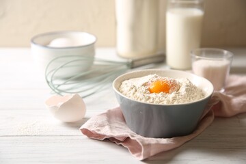 Making dough. Flour with yolk in bowl on white wooden table, closeup
