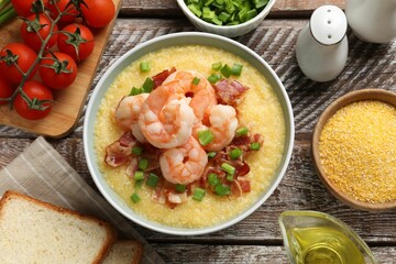 Fresh tasty shrimps, bacon, grits and green onion in bowl on wooden table, flat lay