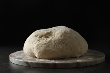 Raw homemade dough and board on black table