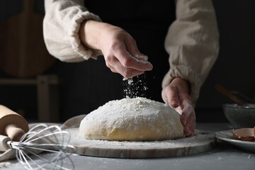 Making dough. Woman adding flour at grey table, closeup
