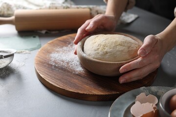 Woman making dough at grey table, closeup