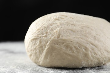 Raw homemade dough and flour on black table, closeup