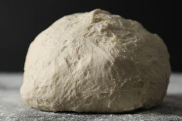 Raw homemade dough and flour on black table, closeup