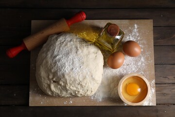 Raw dough, rolling pin and ingredients on wooden table, top view