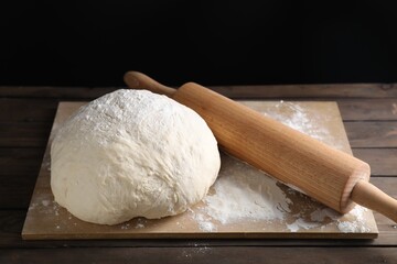 Raw dough and rolling pin on wooden table