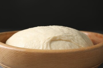 Raw dough in bowl on black background, closeup