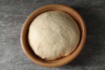 Raw dough in bowl on grey table, top view