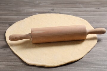 Raw dough and rolling pin on wooden table