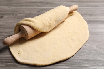 Raw dough and rolling pin on wooden table